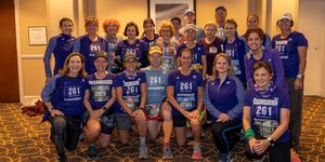 A large group of runners in purple 261 Fearless shirts pose in a room